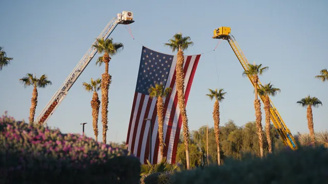 An American flag hangs between two fire-truck ladders at the sunrise remembrance for the victims of the 1 October shooting, Las Vegas.