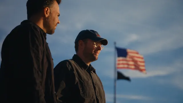Tommy and Josh beneath an American flag in Washington, DC.