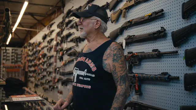 Mel Bernstein in front of the wall of guns at Dragon Arms, Colorado Springs.