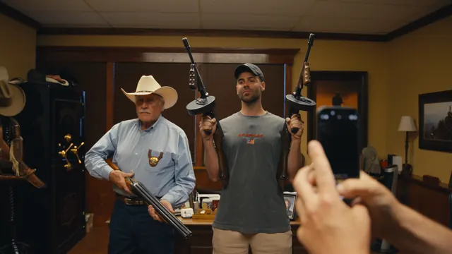 Tommy holds a Tommy gun in each hand beside Sheriff Parnell McNamara in his office in Waco, Texas.